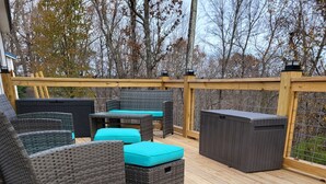 A wooden deck with wicker furniture and a storage unit. - Charming 2-bedroom, 2 full baths and pet friendly house near Mammoth Cave NP. (Mammoth Cave)