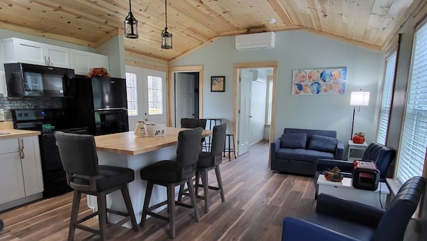 A spacious living area with a wooden floor, a blue sofa, and a dining area with a wooden table and chairs. - Charming 2-bedroom, 2 full baths and pet friendly house near Mammoth Cave NP. (Mammoth Cave)