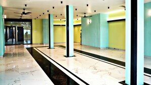 Un hall d’entrée spacieux, doté d’un sol en marbre, de ventilateurs de plafond et de murs de couleur turquoise.