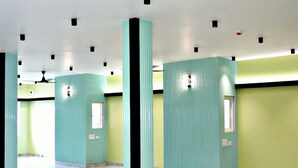 Un hall d’entrée spacieux doté d’un sol en marbre, de piliers de couleur turquoise et de murs verts.
