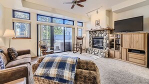 A cozy living room with a fireplace, a television, and a comfortable seating area with a sofa and chairs. - Village Point #212: Private Hot Tub and Easy Access to Town and Slopes (Breckenridge)
