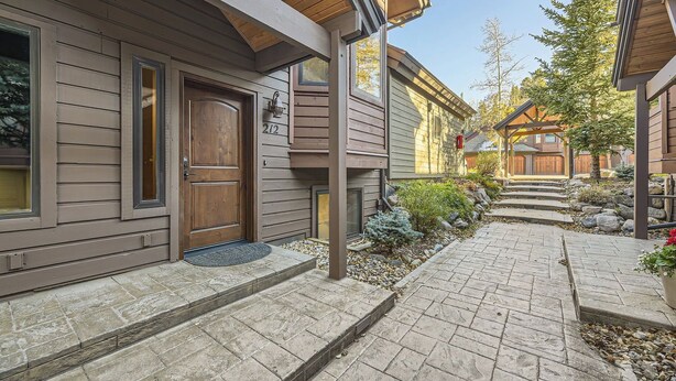 A residential building with a wooden exterior, a front door, and a stone-paved entrance. - Village Point #212: Private Hot Tub and Easy Access to Town and Slopes (Breckenridge)