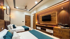 A modern hotel room with two beds, a TV, wooden paneling, and a ceiling fan. - Hotel Brij Vas (Mathura)