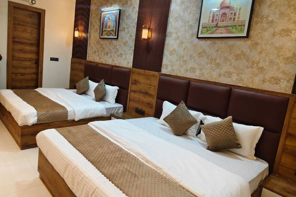 A hotel room with two beds, wooden headboards, and wall-mounted artwork.
