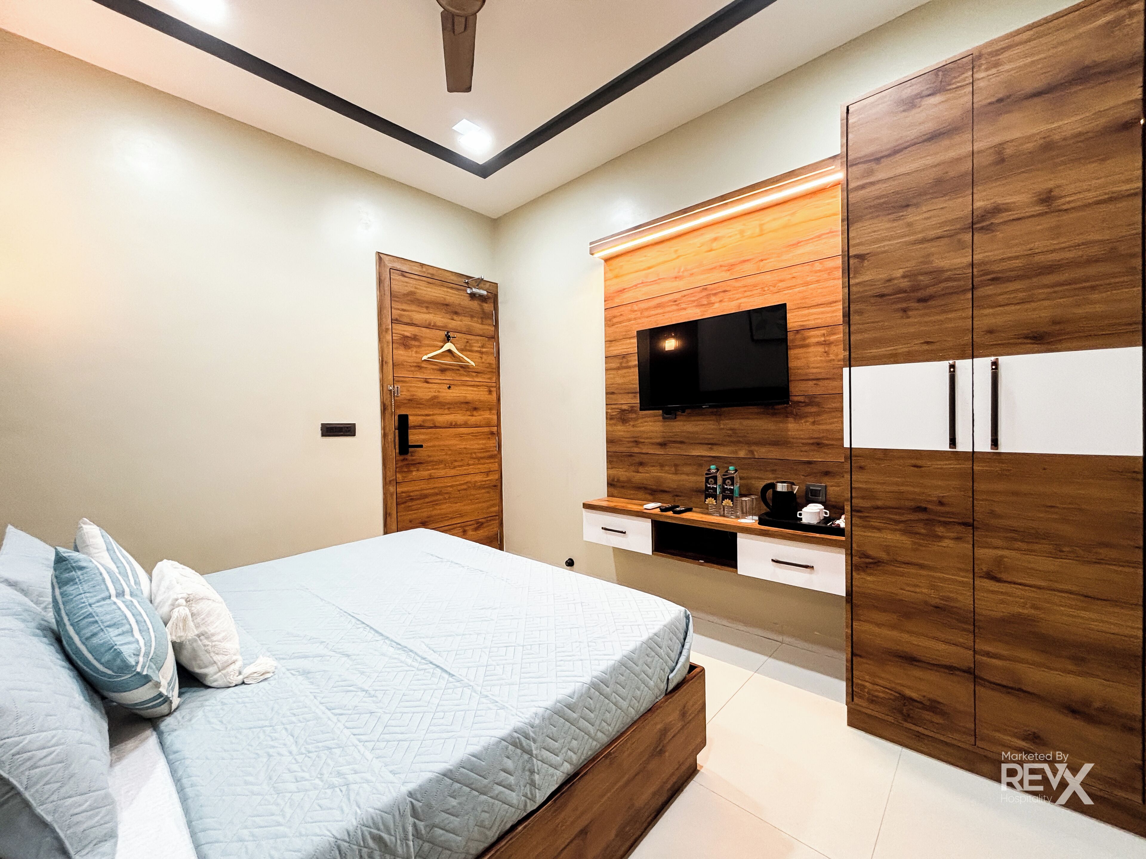 A modern bedroom with a bed, wooden wardrobe, TV, and a coffee machine.