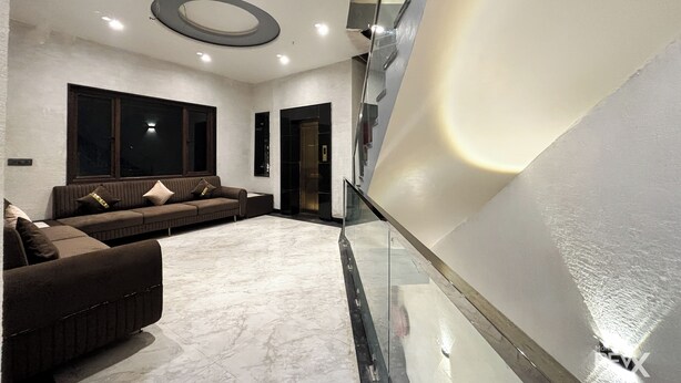 A modern living area with a sofa set, a glass railing, and a marble floor. - Hotel Brij Vas (Mathura)