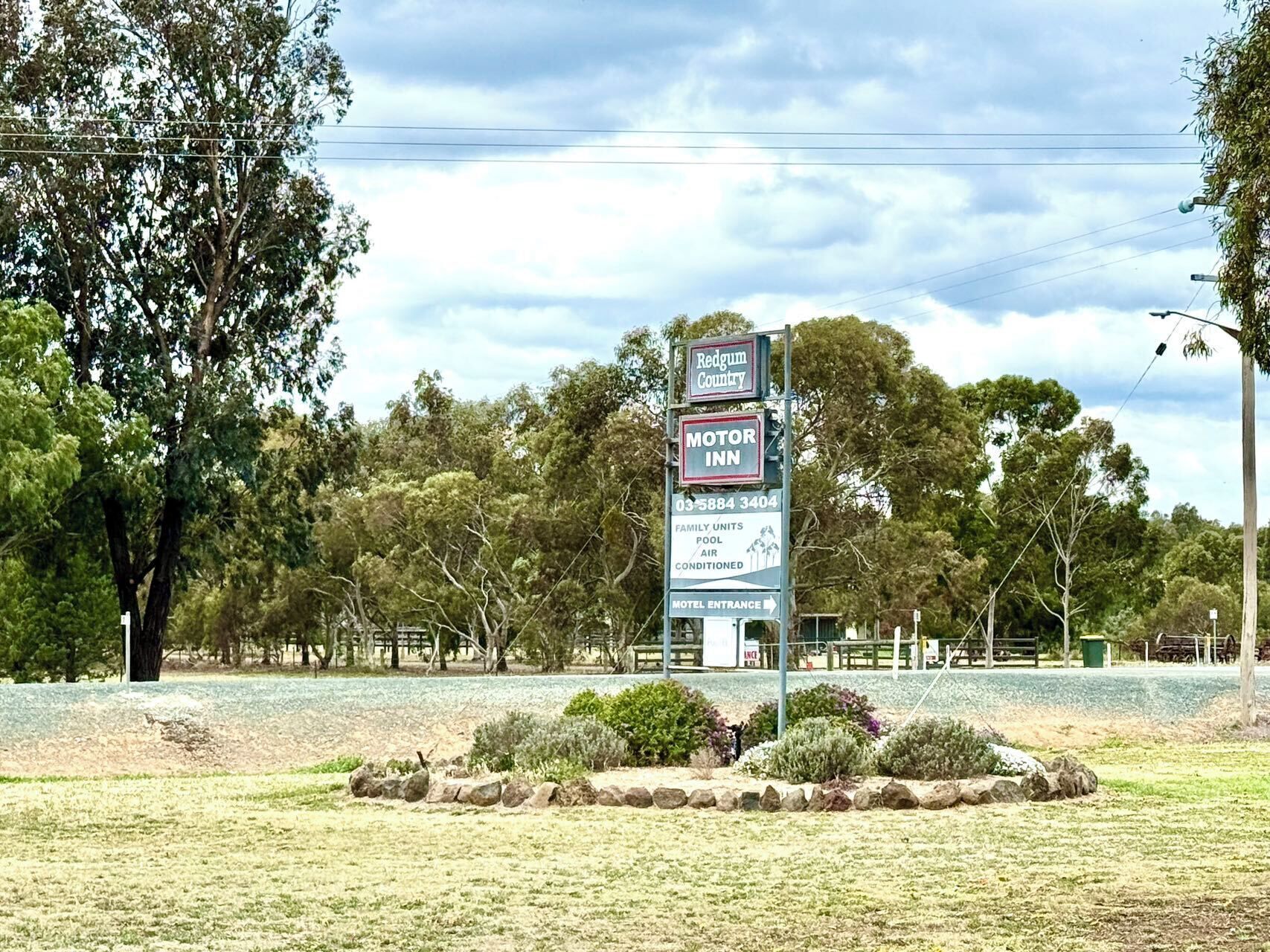 A motel signboard with amenities including family units, pool, air conditioning, and a motel entrance.