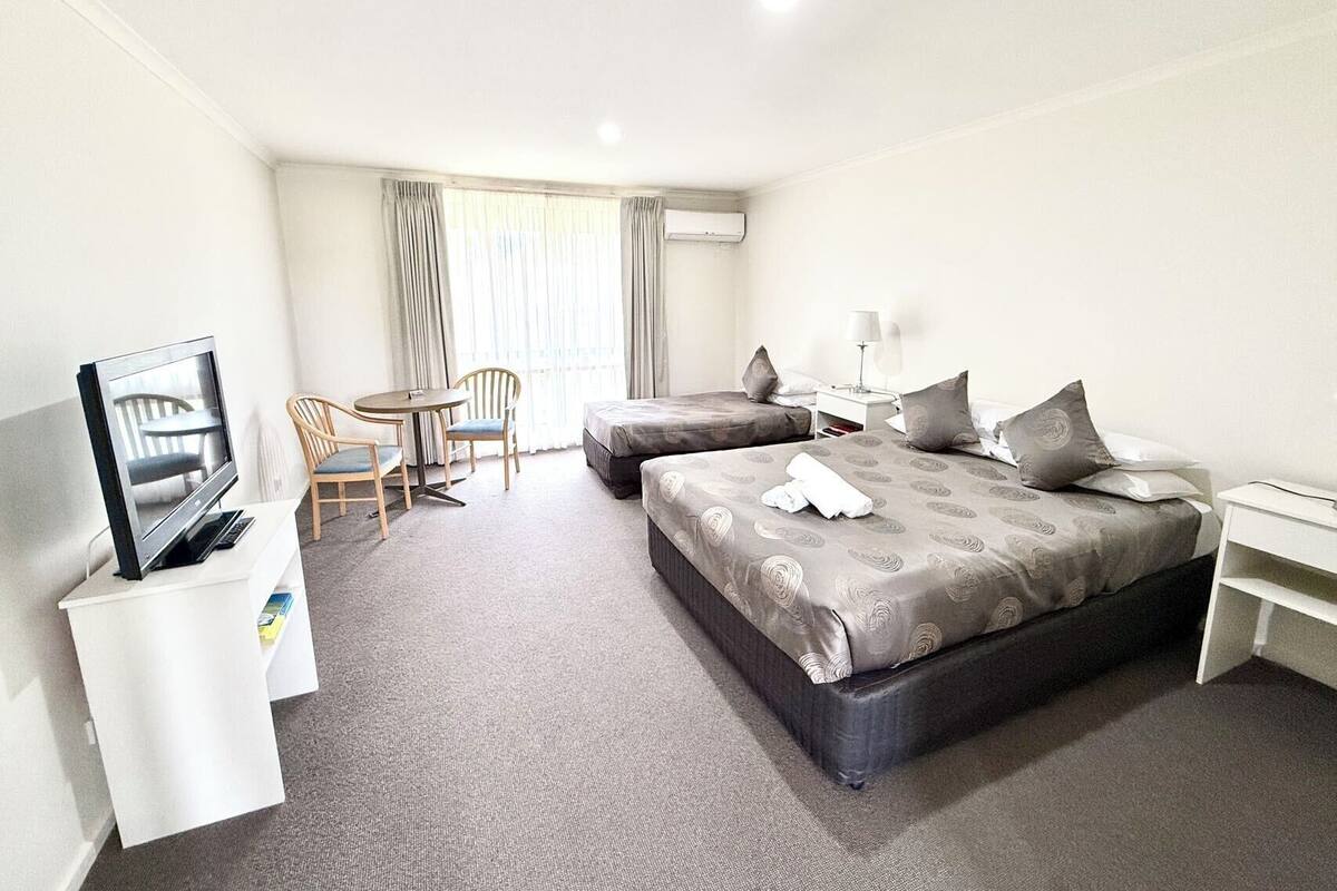 Habitación de hotel con dos camas, televisión, escritorio y una silla.