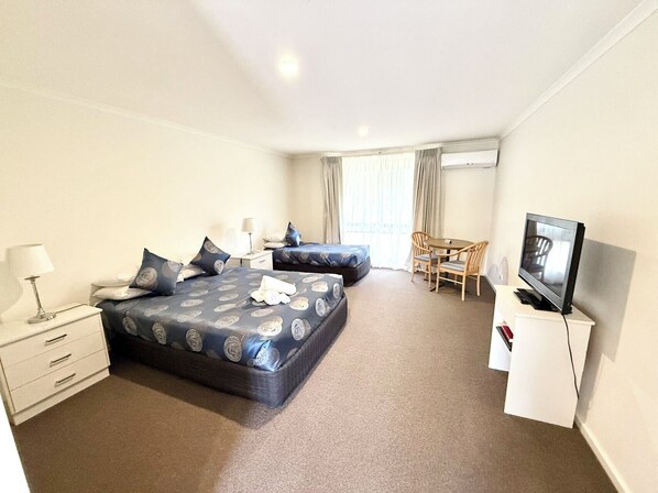 A hotel room with two beds, a desk, a chair, a television, and a window with curtains.