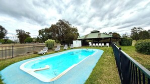 A swimming pool with lounge chairs and a pavilion. - Redgum Motel (Mathoura)