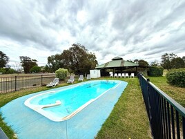 Uma piscina com espreguiçadeiras e um pavilhão.