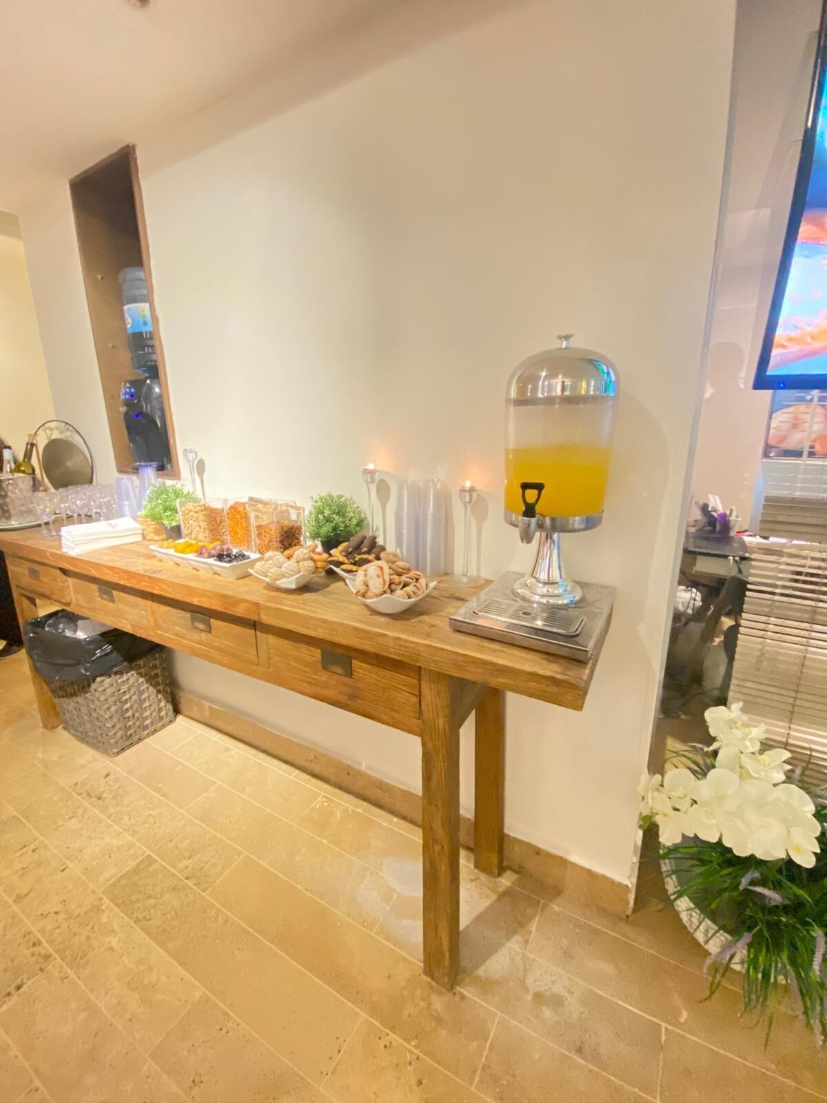 A buffet table with various food items and a juice dispenser.