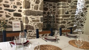 A dining table set with wine glasses, plates, and cutlery, set against a stone wall with a decorative lantern. - At the heart of a market-garden farm on the Emerald Coast  (Saint-Lunaire)