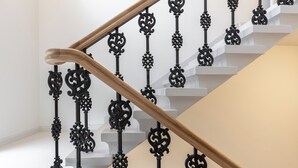 Una escalera con barandillas de metal negro ornamentado y un pasamanos de madera.