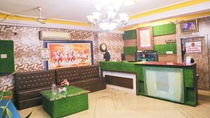 Un área de recepción con alfombra verde, un mostrador de recepción, un sofá y una araña de cristal.