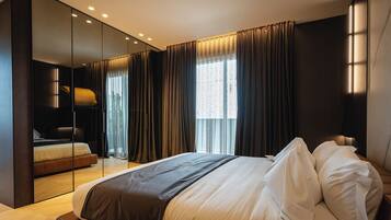 A modern hotel room with a large bed, a separate seating area, a large mirror, and a view of the outdoors.