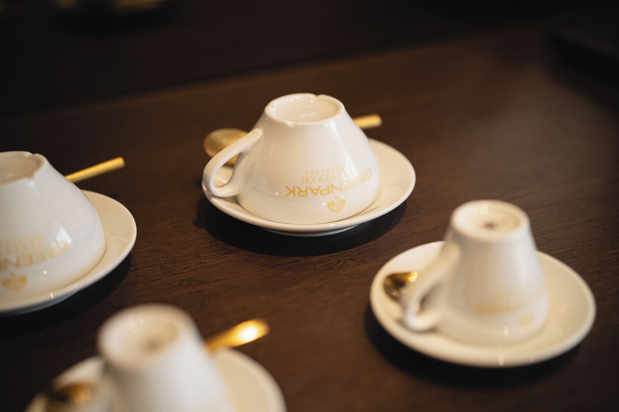 A table with several white cups and saucers, some with gold detailing.