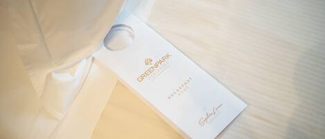 A white tag with the text "GREENHOUSE PENINSULA SUITESPOOL" and "BREAKFAST MENU" on a wooden surface.