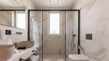 A modern bathroom with a large mirror, two sinks, a shower enclosure, and a toilet.