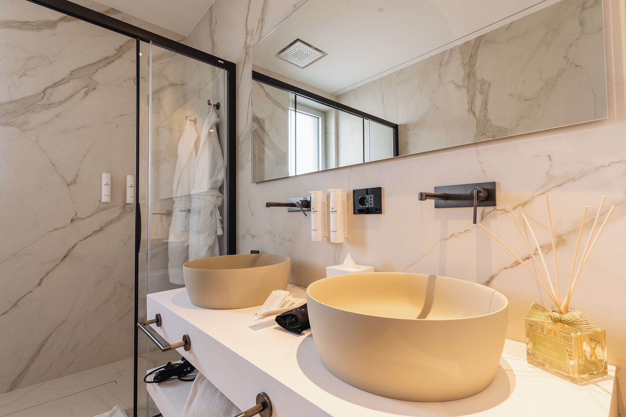 A modern bathroom with two large sinks, a large mirror, and a glass shower enclosure.