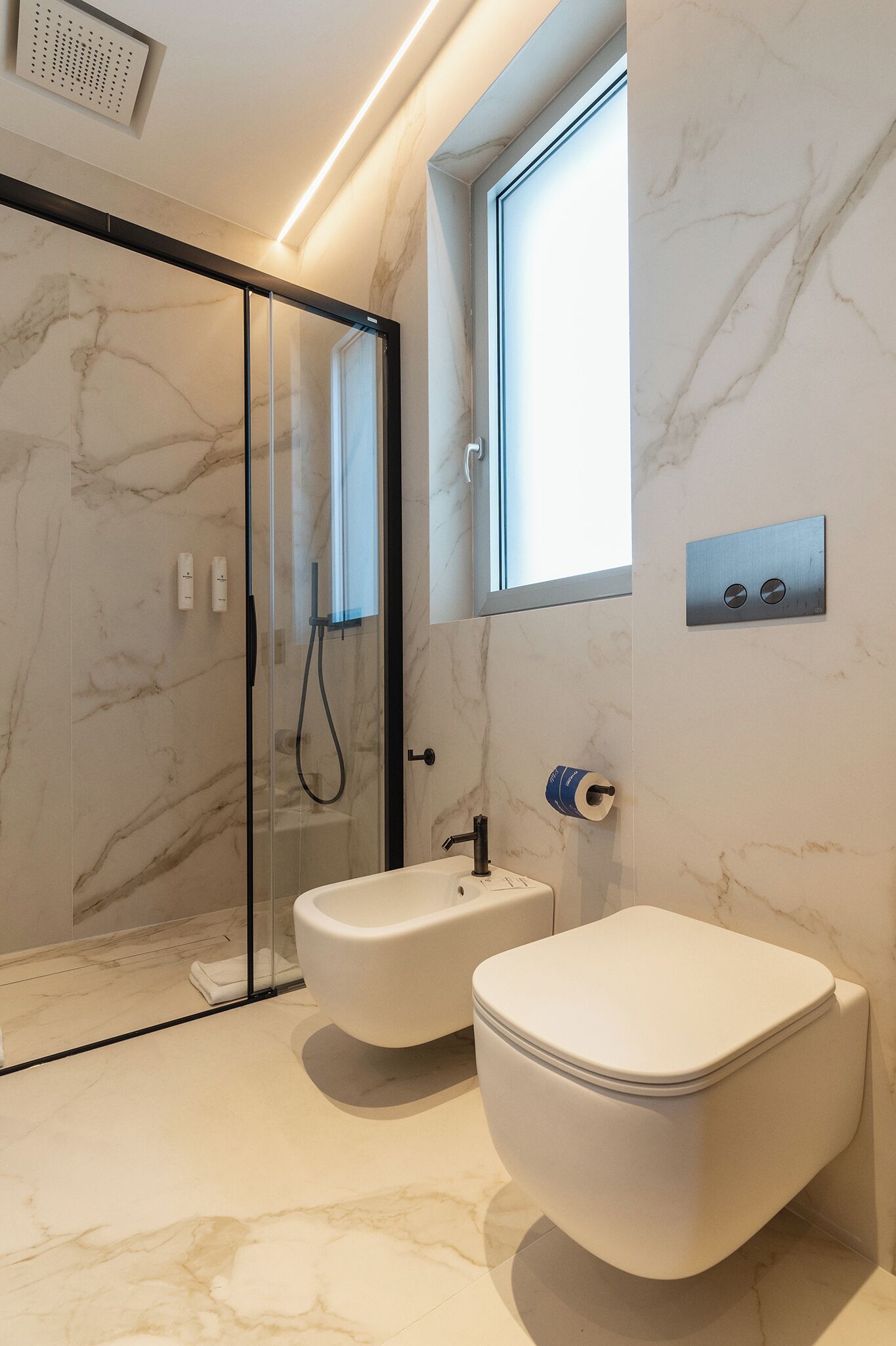 Un baño con ducha de vidrio, inodoro blanco y lavamanos.