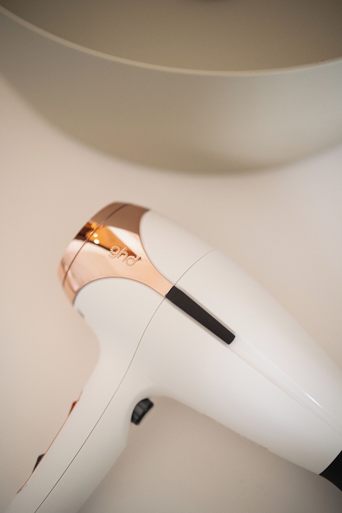 A white hair dryer with a metallic top and a black control panel.