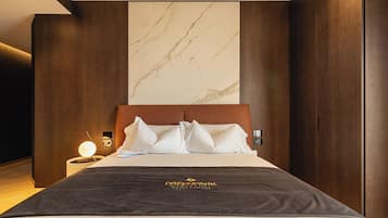 A hotel room with a large bed, a marble wall, wooden paneling, and a nightstand with a lamp.
