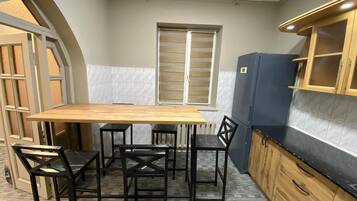 Una cocina compacta con una mesa y sillas de madera, un refrigerador y armarios de madera.