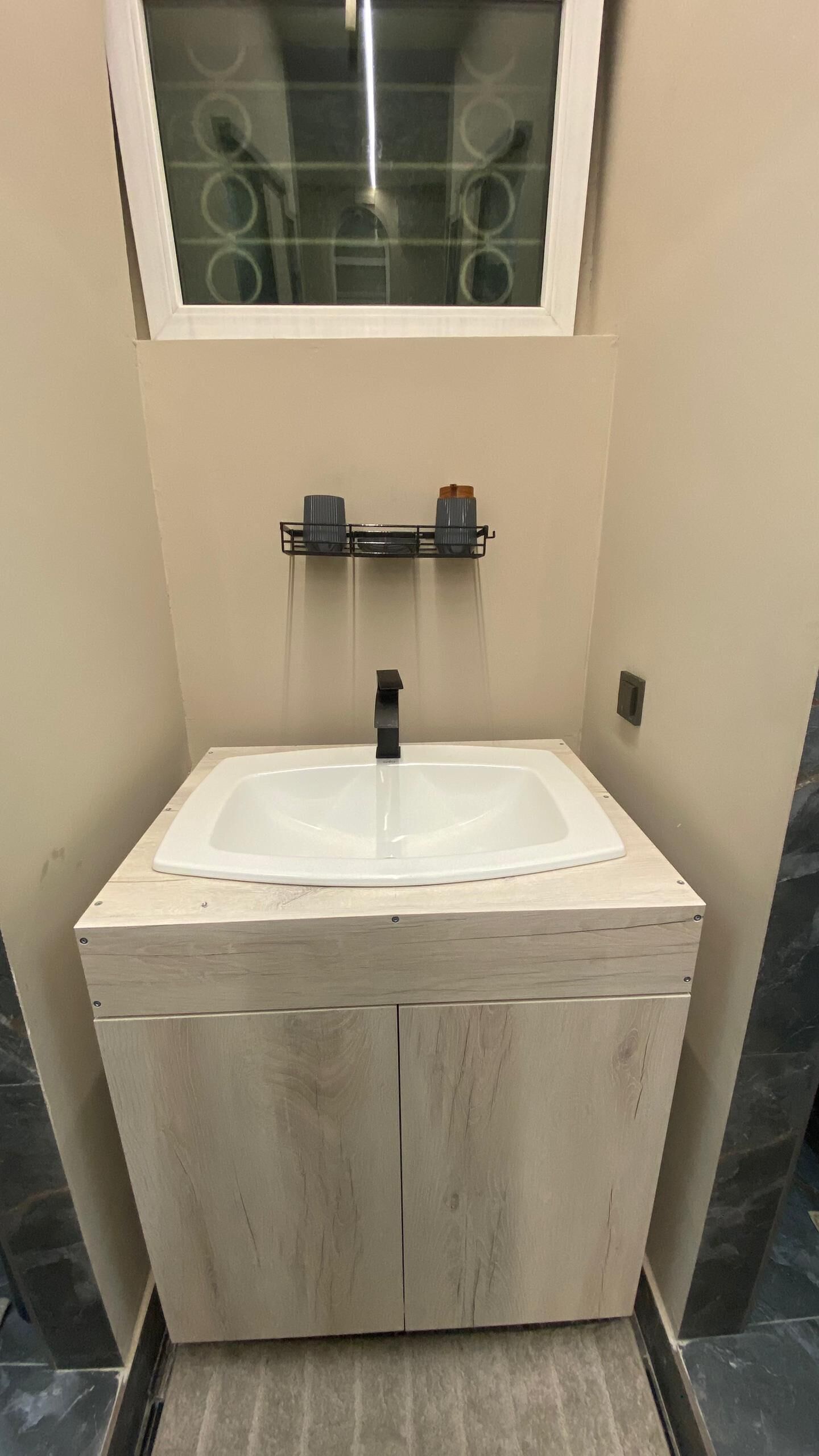 A bathroom with a white sink, wooden cabinetry, and a mirror above the sink.