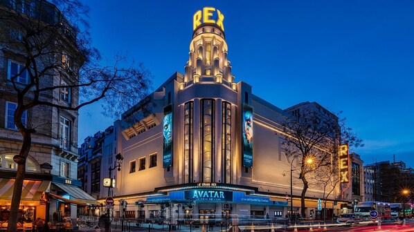 A grand cinema with a prominent marquee reading "REX" and "AVATAR" displayed on its facade.