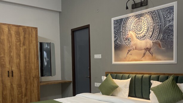 A bedroom with a large bed, a wardrobe, a door, and a wall-mounted artwork. -  SG Boutique Stay (Near Railway Station) (Udaipur)
