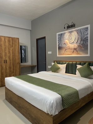 A bedroom with a large bed, a wardrobe, a door, and a wall-mounted artwork. -  SG Boutique Stay (Near Railway Station) (Udaipur)