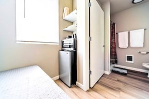 Compact room with a bed, kitchenette, and refrigerator.