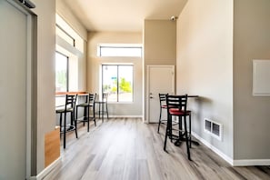 Enter a spacious hallway leading to a dining area with two tables and comfortable seating.