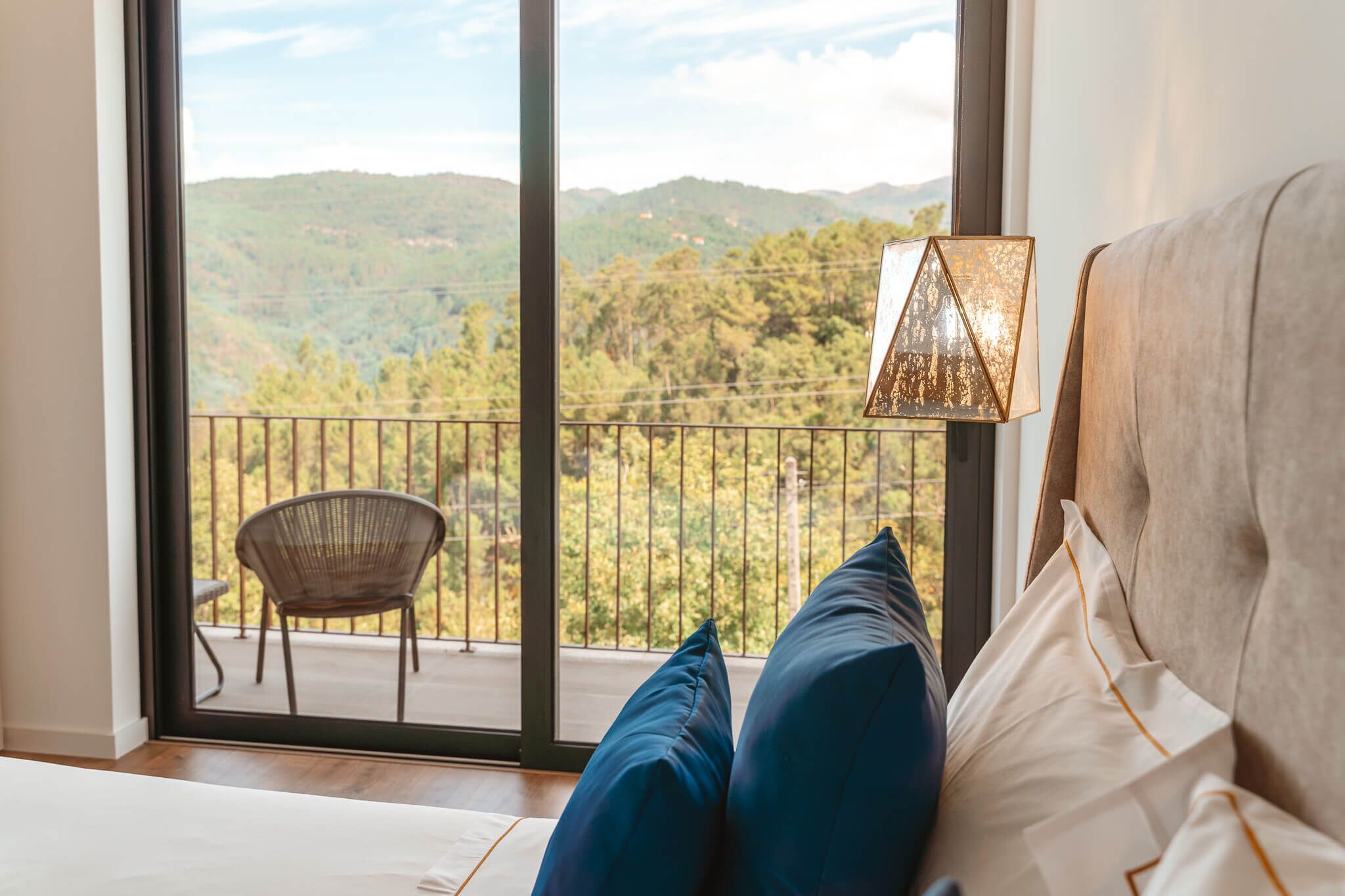 Un dormitorio con vistas a un paisaje montañoso a través de una puerta de balcón.