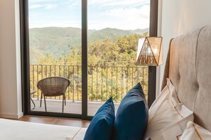 A bedroom with a view of a mountainous landscape through a balcony door. - Encosta de Louredo by Pousadela Village (Vieira do Minho)