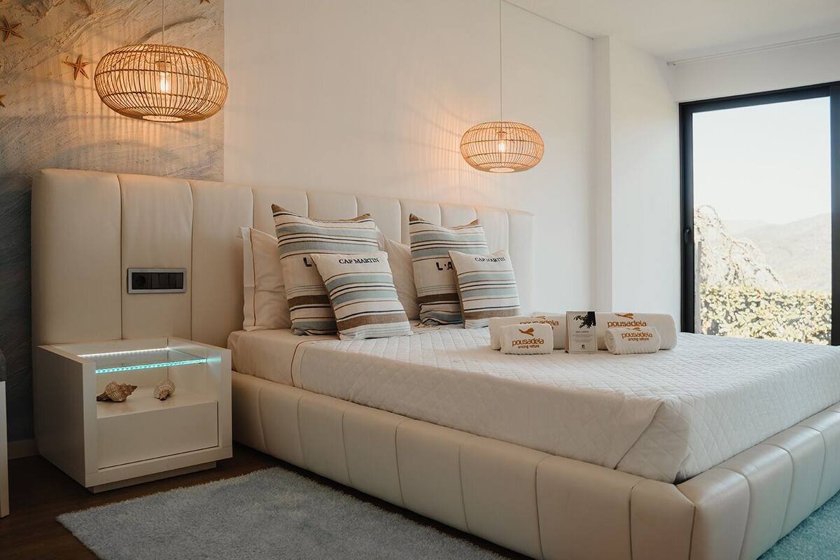 Une chambre à coucher moderne avec un grand lit, deux tables de chevet et une petite table d’appoint.