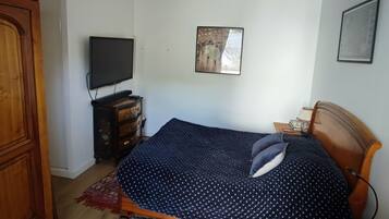 Een slaapkamer met een bed, een televisie, een dressoir en een hanglamp.