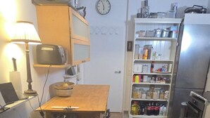 Une cuisine compacte comprenant une table à manger, un réfrigérateur et une étagère où sont rangés divers objets.