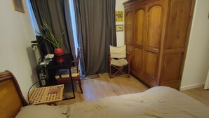 Une chambre à coucher comprenant un lit, une armoire en bois, un bureau avec une chaise et une fenêtre avec des rideaux.