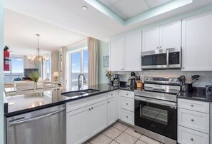 Una cocina moderna con armarios blancos, electrodomésticos de acero inoxidable y una isla grande con un lavamanos.