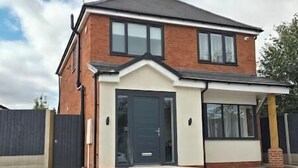 A two-story house with a front garage, a covered porch, and a brick facade. - Welcome to our centrally-located 4-bedroom detached new build home in Stafford (Stafford)