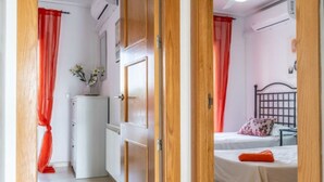 A compact bedroom with a single bed, a small bedside table, and a window with red curtains. - Casa Viv - Beautiful Spacious 2 bed apartment in the lovely La Torre Golf Resort (Torre-Pacheco)