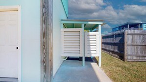 Ein Haus mit einer überdachten Veranda, einem Holzzaun und einem Betonweg.