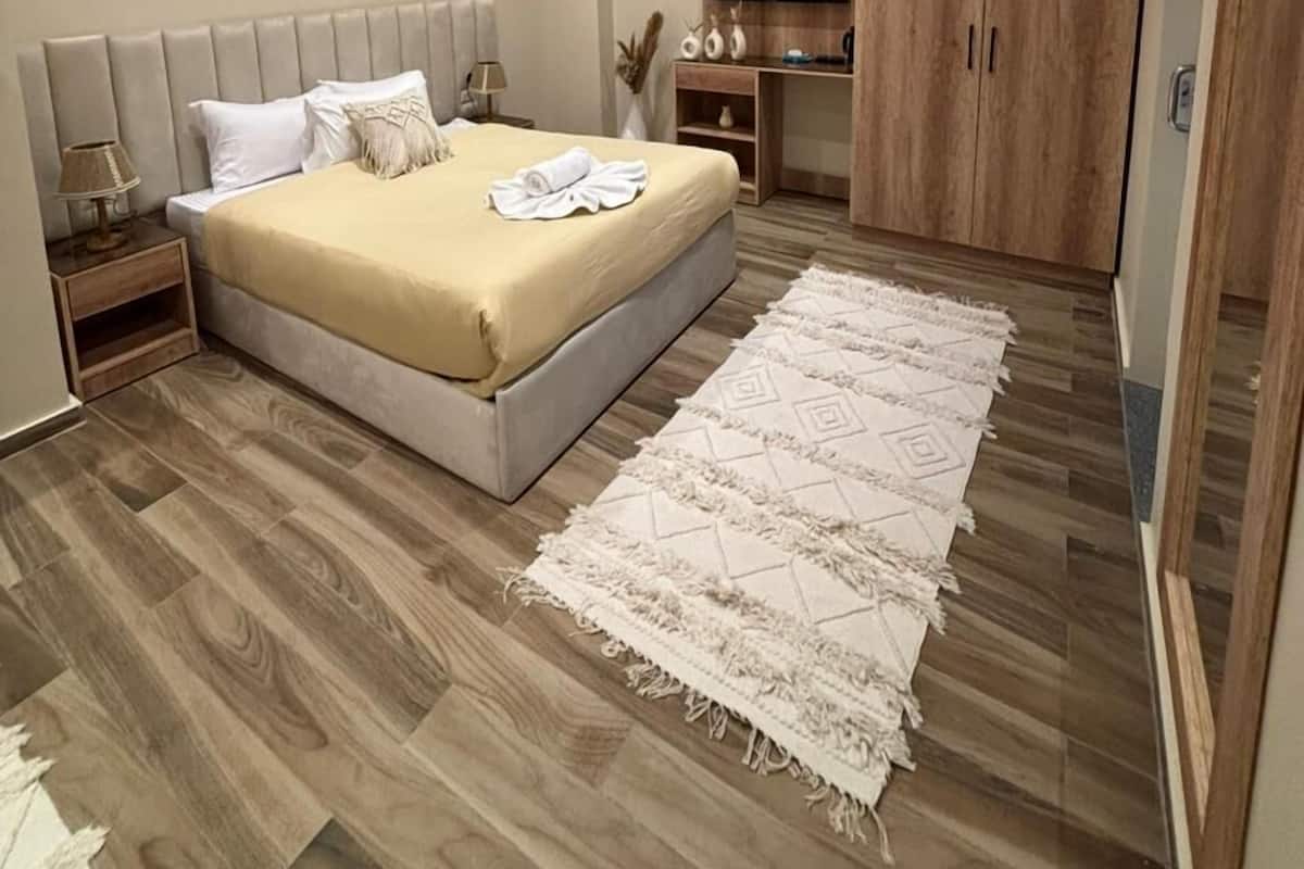 A modern bedroom with a large bed, bedside tables, a TV, and wooden wardrobe.