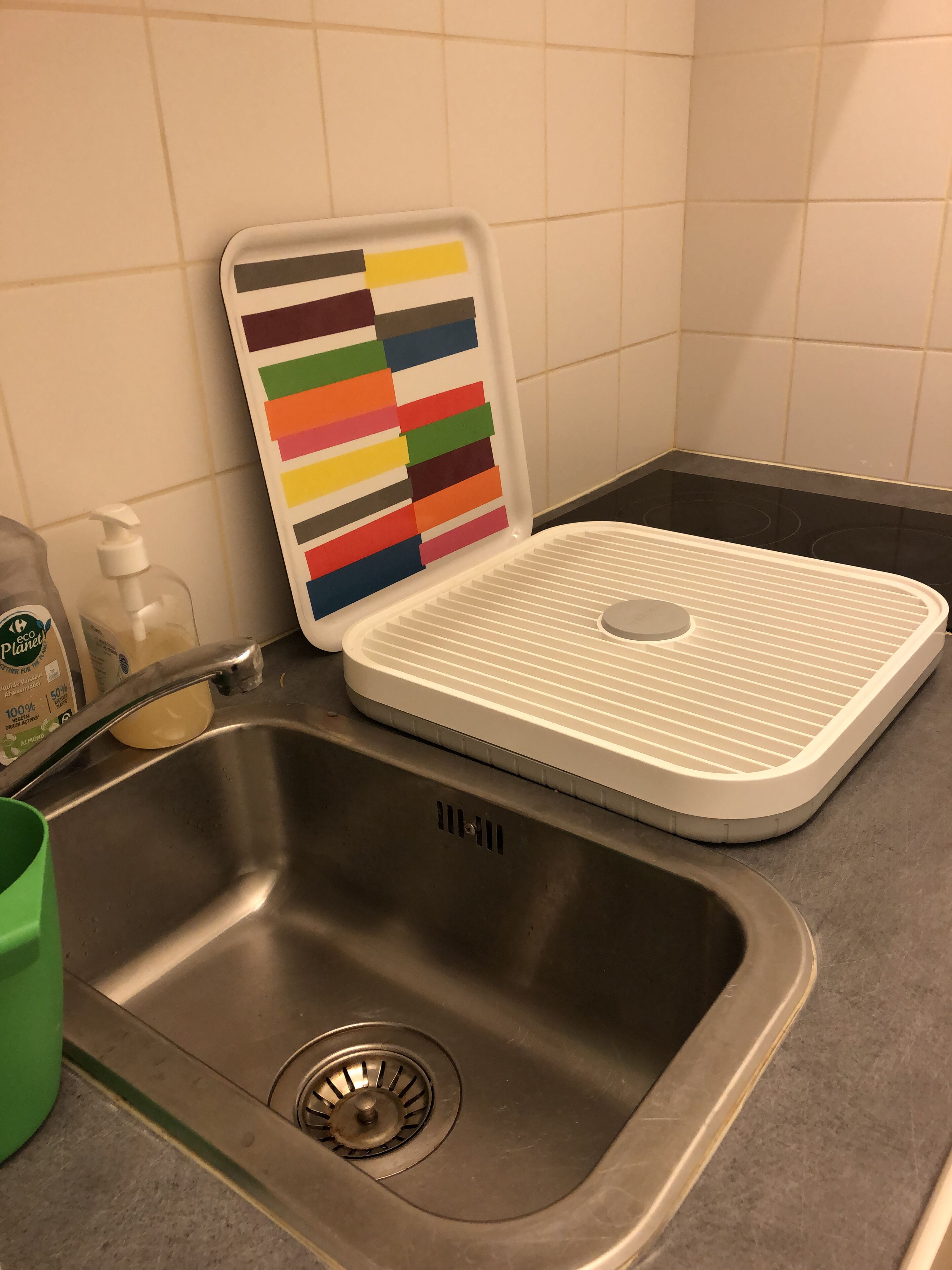 A kitchen sink with a modern faucet and a colorful soap dispenser.
