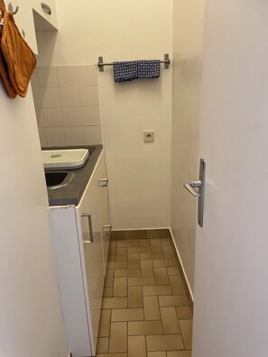 Et lille, smalt badeværelse med toilet, vask og håndklædestang.