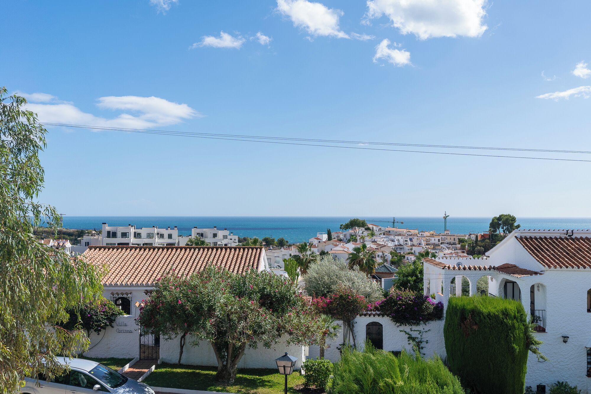A coastal town with white buildings, a clear blue sky, and a view of the sea.