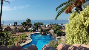 Ein Pool mit Meerblick, umgeben von Palmen und Gebäuden.