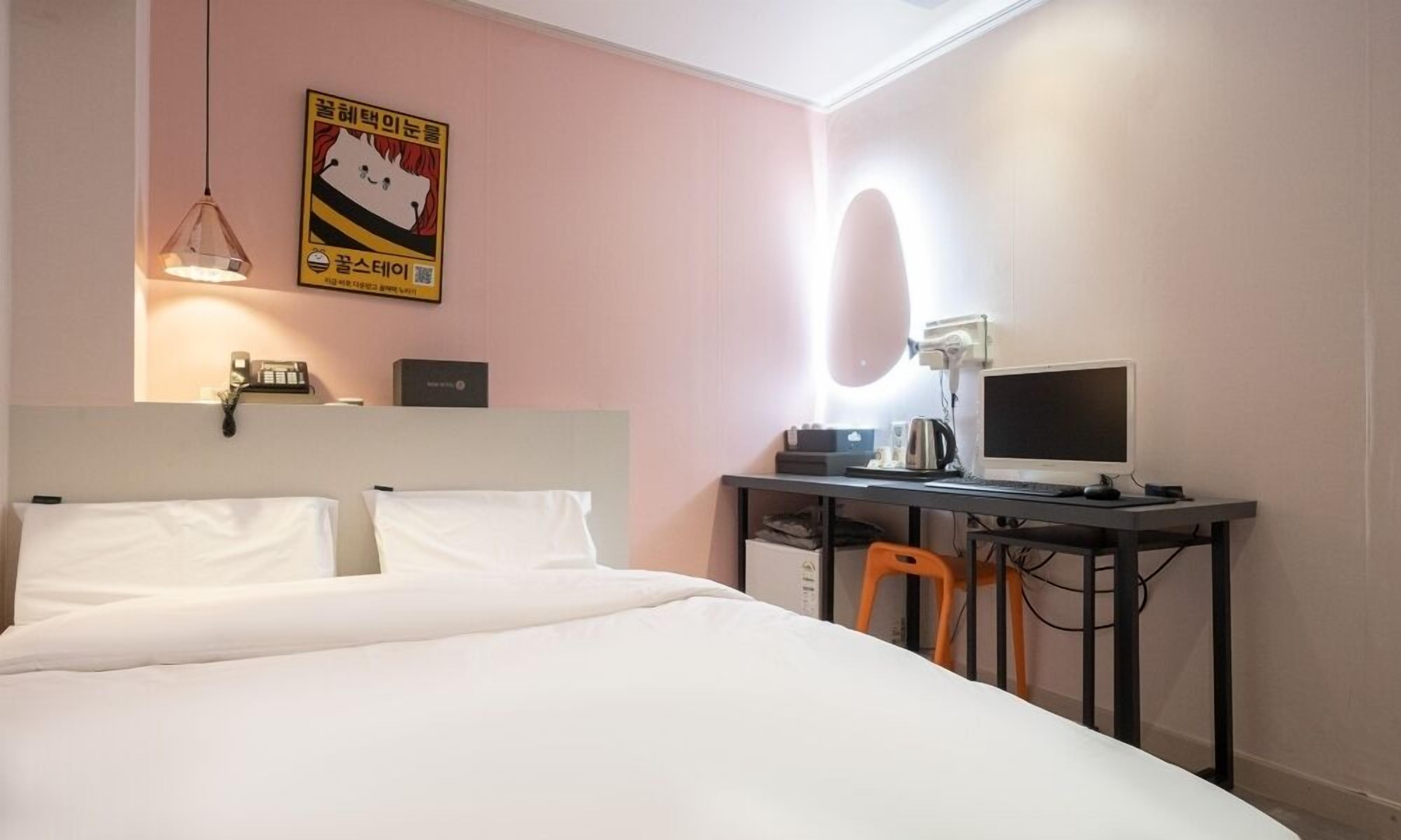 Ein Hotelzimmer mit Bett, Schreibtisch, Computer und einem Bild an der Wand.